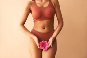 Mulher segurando uma flor próxima à região pélvica, representando saúde íntima e cuidado com a secreção vaginal