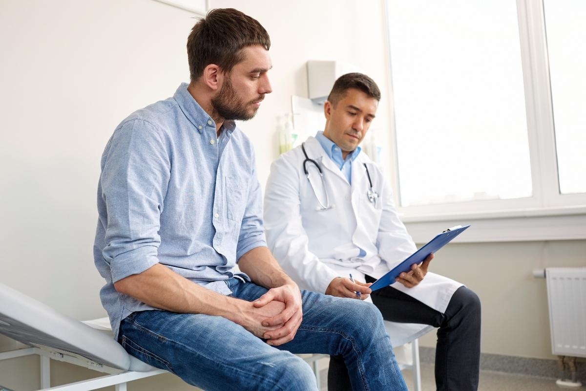 Homem de cerca de 30 anos em consulta médica realizando check-up de rotina, representando a importância de exames preventivos para a saúde masculina