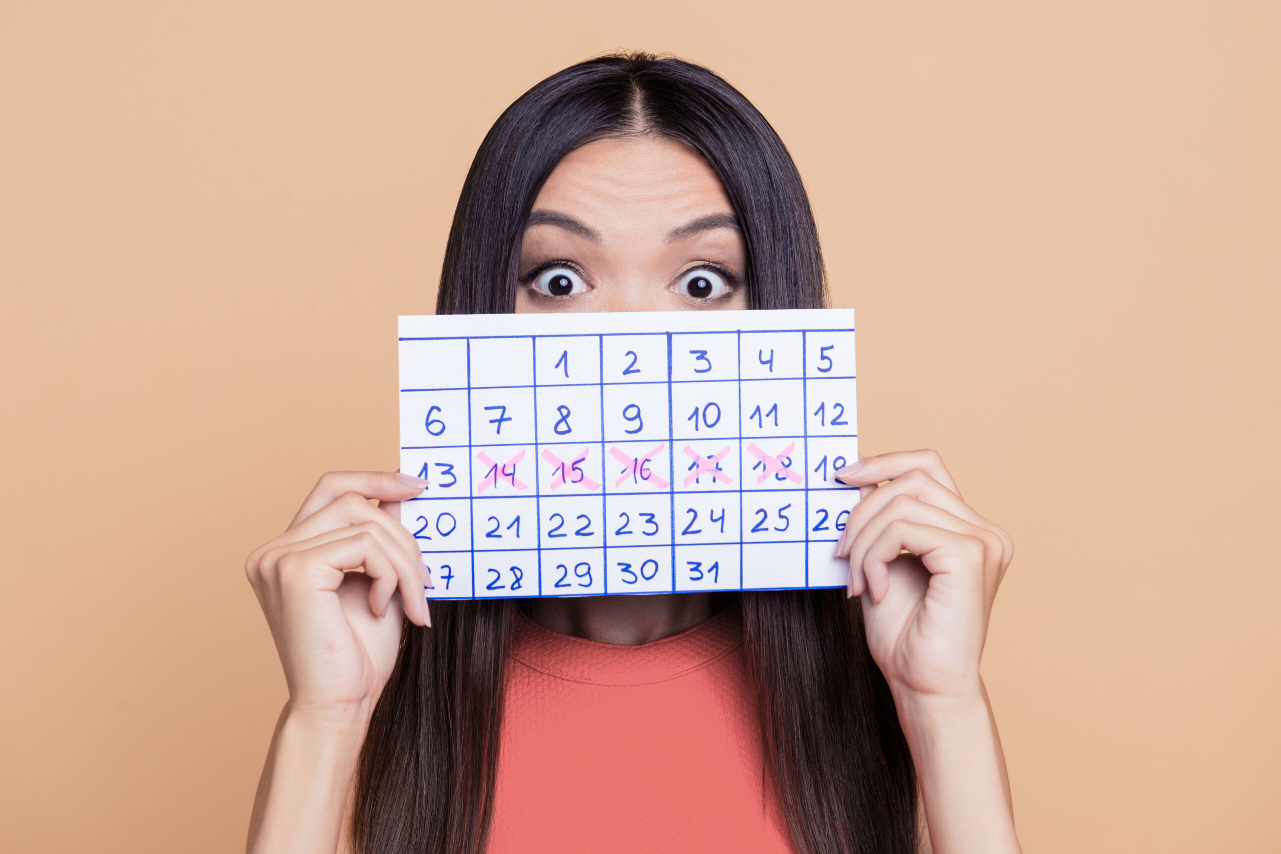 Mulher segura calendário com ciclo menstrual marcado, representando atenção à saúde feminina e regularidade da menstruação