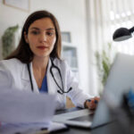 Profissional de saúde lendo documentos em consultório, representando checagem de mitos e crenças sobre saúde
