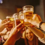 Grupo de amigos brindando com copos de cerveja durante encontro social noturno