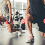 Duas pessoas treinando com halteres na academia, ilustrando treino de hipertrofia para iniciantes em 3 dias na semana