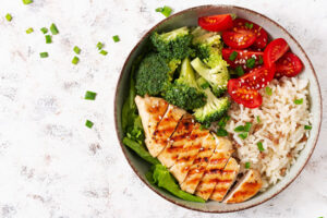 Prato com arroz branco, frango grelhado e legumes, refeição rica em proteínas para hipertrofia muscular